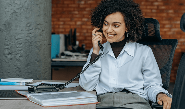 kvinna-telefon-skrivbord-glad