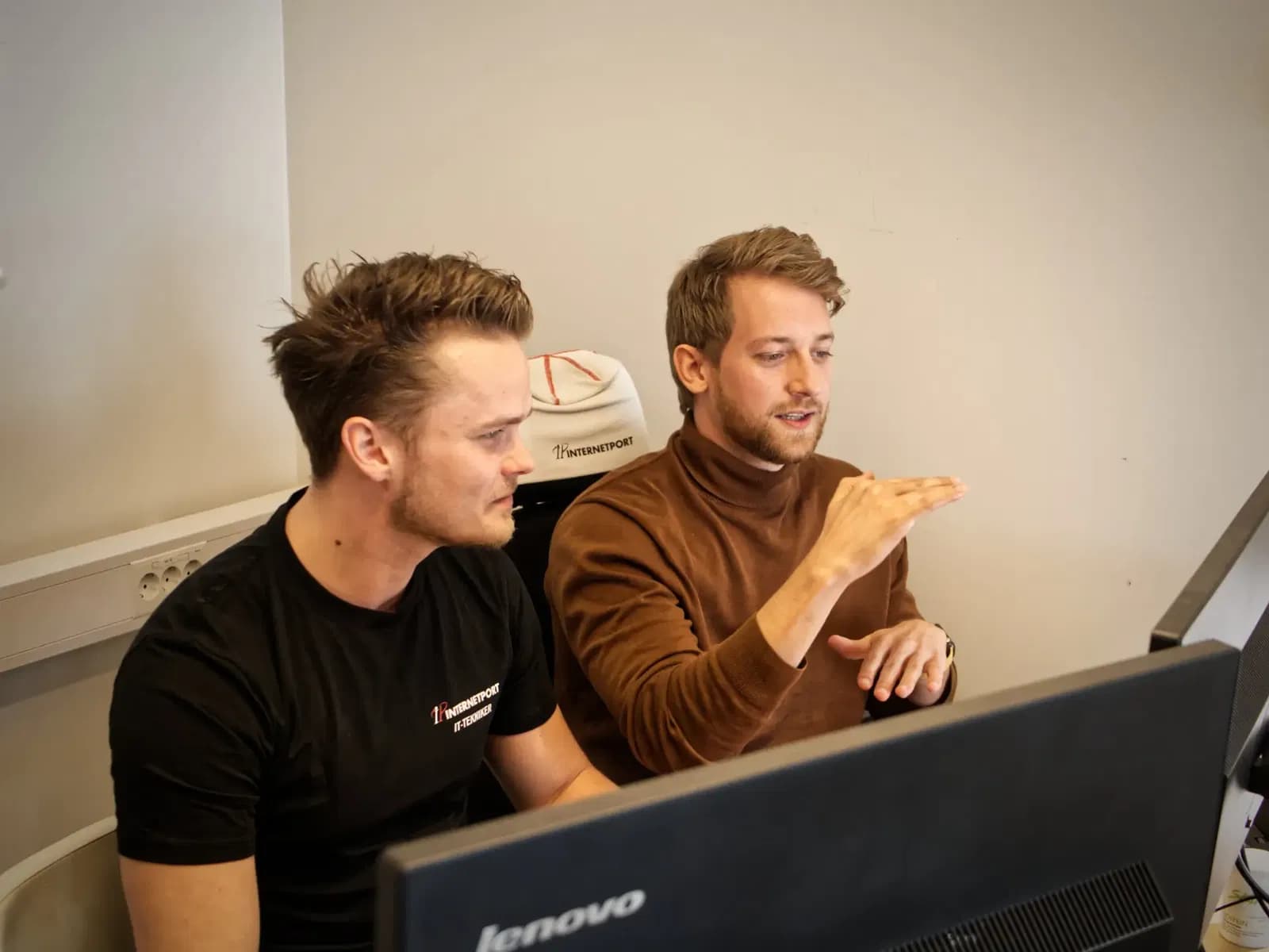 Två personer från kundtjänst som hjälper en kund framför en datorskärm.